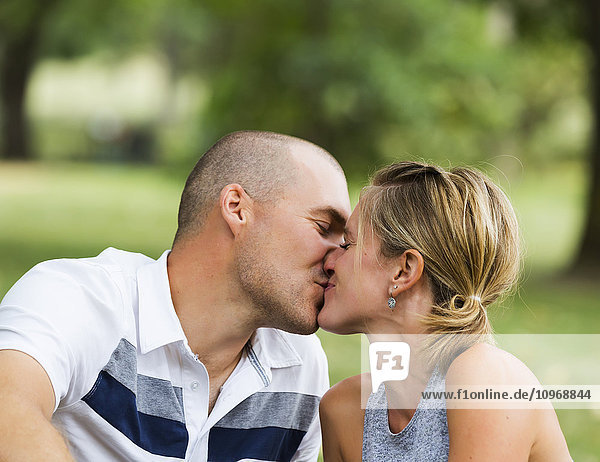 Ein Mann und eine Frau küssen sich in einem Park; Edmonton  Alberta  Kanada'.