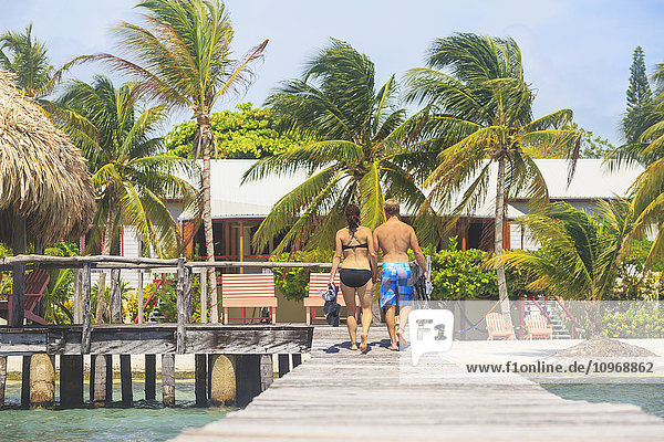 Ein Paar  das auf einem Holzsteg spazieren geht  Saint Georges Caye Resort; Belize City  Belize'.