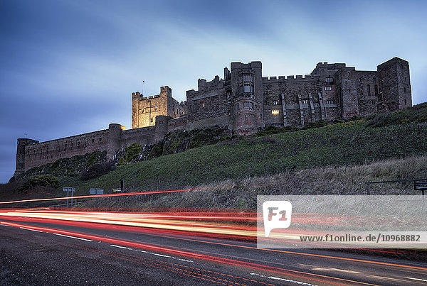 Lichtspuren auf der Straße und Bamburgh Castle; Bamburgh  Northumberland  England'.