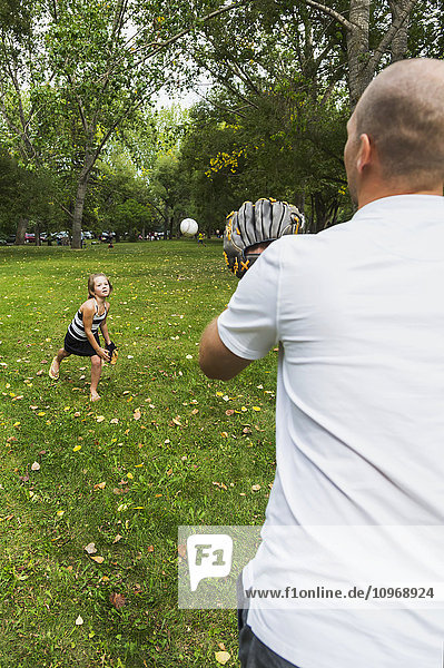 'Father and daughter playing baseball in a park; Edmonton  Alberta  Canada'