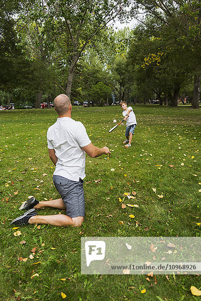 'Father and son playing baseball in a park; Edmonton  Alberta  Canada'