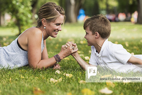 'Mother arm wrestling with her son in a park during a family outing; Edmonton  Alberta  Canada'