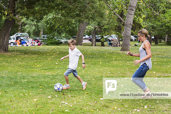 'A mother playing soccer with her son in a park during a family outing; Edmonton  Alberta  Canada'