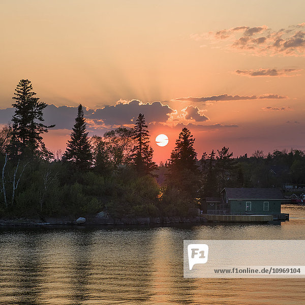 Cottage am Rande eines Sees bei Sonnenaufgang mit rosa Himmel  Lake of the Woods; Kenora  Ontario  Kanada'.