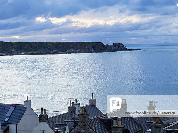 Klippen entlang der Küste und Dächer von Häusern im Vordergrund; Cullen  Moray  Schottland