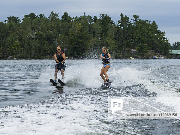 'A young couple waterskiing side by side on a lake; Ontario  Canada'