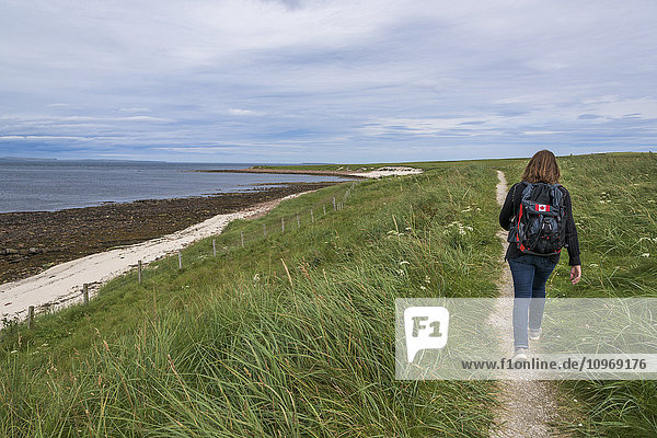Ein Mann mit Rucksack geht auf einem Wanderweg entlang der Küste; John O'Groats  Schottland'.