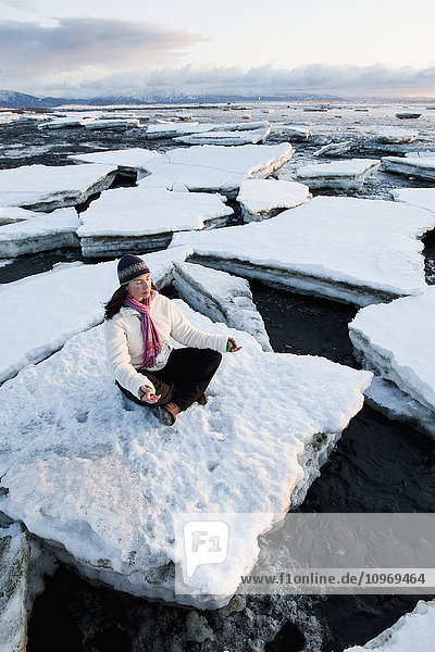 Woman practicing meditation on ice chunks stacked against the Homer Spit  Southcentral Alaska