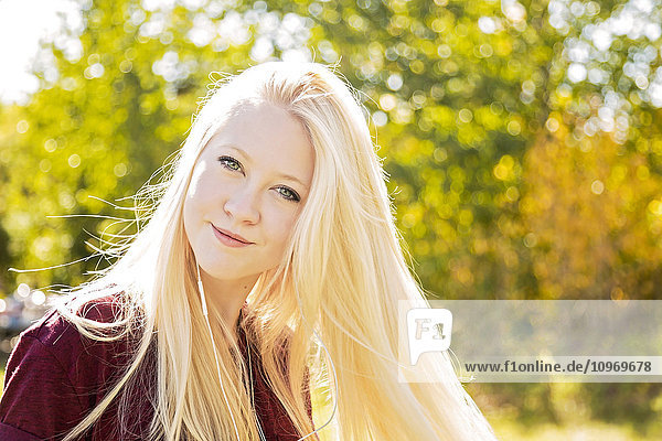 'Outdoor portrait of a beautiful young woman with long blond hair in a city park in autumn; Edmonton  Alberta  Canada'
