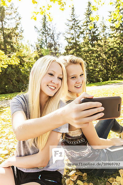 Zwei Schwestern  die im Herbst in einem Stadtpark Spaß haben und ein Selfie machen; Edmonton  Alberta  Kanada'.