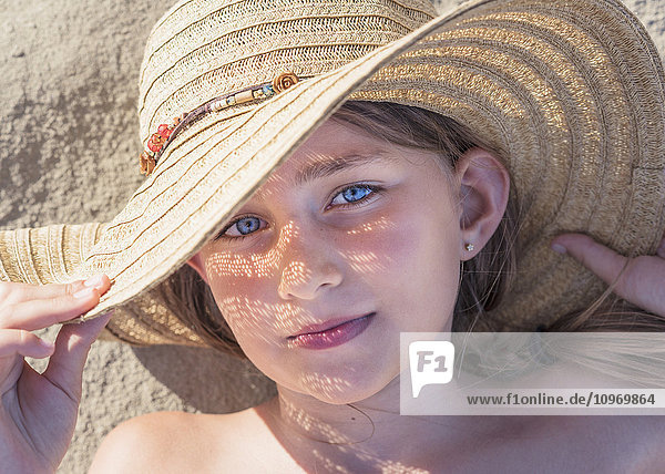 'A girl laying on the sand wearing a sunhat; Tarifa  Cadiz  Andalusia  Spain'