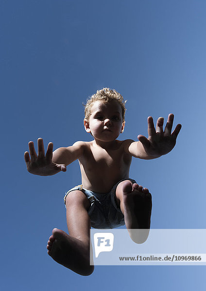 'Low angle view of a child in mid-air against a blue sky; Tarifa  Cadiz  Andalusia  Spain'