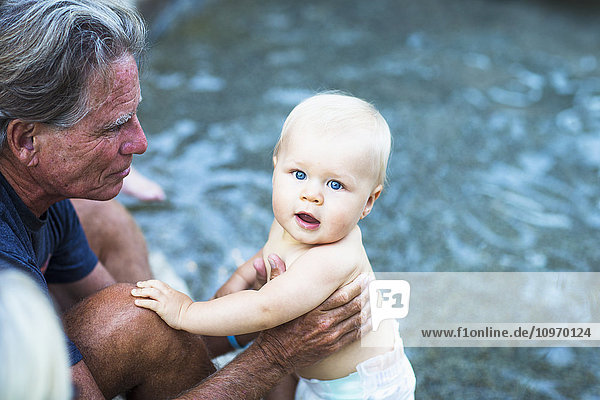 Ein Großvater hält ein kleines Baby am Pool; Fountain Valley  Kalifornien  Vereinigte Staaten von Amerika'.