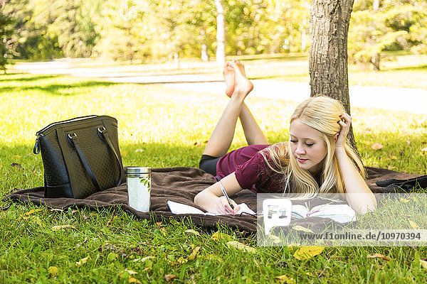 Eine junge Frau verbringt ihre persönliche Zeit mit Bibelstudium im Freien in einem Park im Herbst; Edmonton  Alberta  Kanada'.