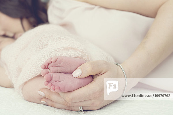 Eine Mutter liegt auf einem Bett und hält mit ihren Händen die Füße eines Neugeborenen; Toronto  Ontario  Kanada'.