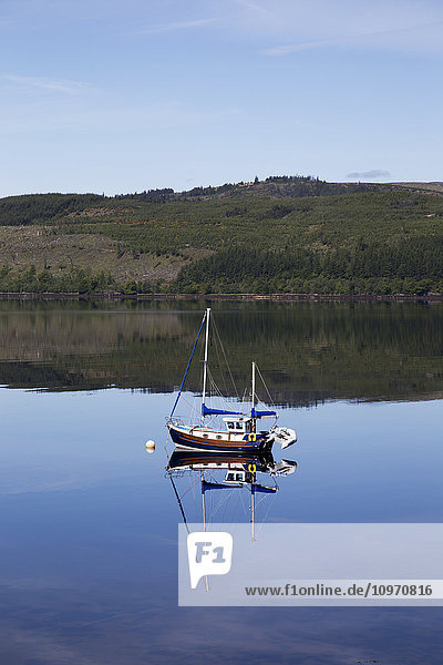 Ein Segelboot  das inmitten eines ruhigen Sees vertäut ist; Strachur  Schottland