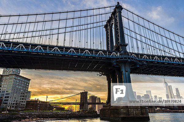 Manhattan- und Brooklyn-Brücke bei Sonnenuntergang  Brooklyn Bridge Park; Brooklyn  New York  Vereinigte Staaten von Amerika'.