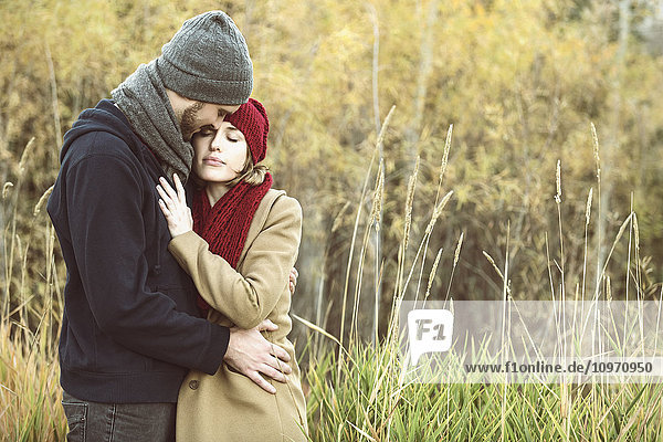 'A young couple holding each other closely in a city park in autumn; Edmonton  Alberta  Canada'