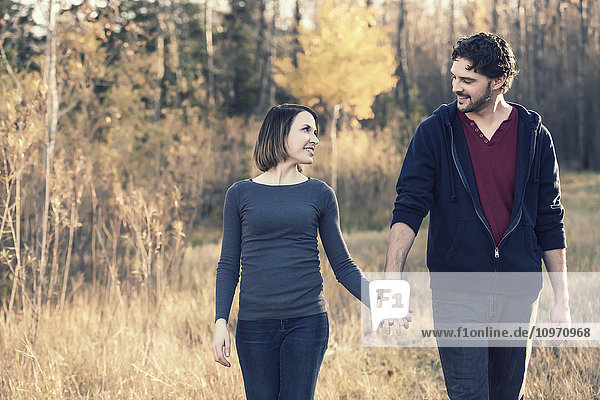 'A young couple walking and enjoying each other's company in a city park in autumn; Edmonton  Alberta  Canada'