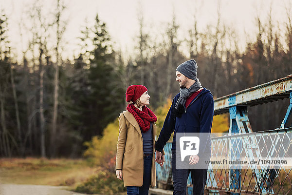 'A young couple walking on a bridge in a city park in autumn; Edmonton  Alberta  Canada'