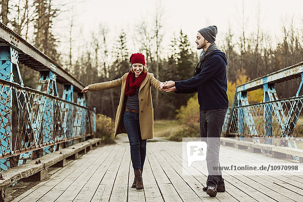 Ein junges Paar  das auf einer Brücke in einem Stadtpark im Herbst zu tanzen vorgibt; Edmonton  Alberta  Kanada'.