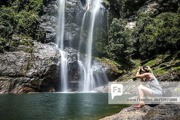 Eine junge Frau fotografiert den Cunca Rami Wasserfall; Flores  Indonesien'.