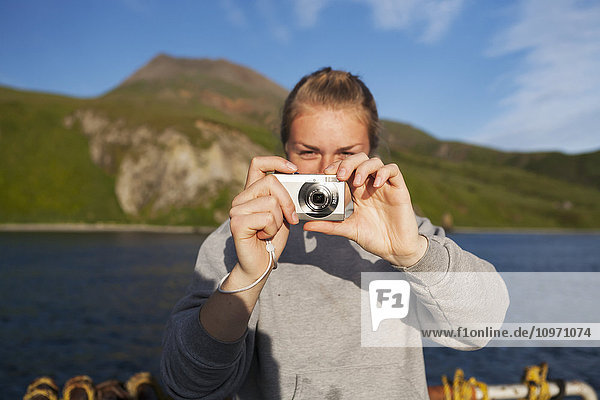 Eine Frau  die ein digitales Foto macht  während sie auf dem Wasser in False Pass  auch bekannt als Isanotski Strait; Südwest Alaska  Vereinigte Staaten von Amerika'.