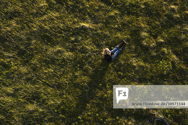 'High Angle View Of A Girl Sitting In A Grass Field; False Pass  Alaska  United States Of America'