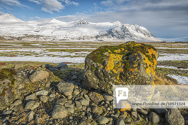 'Moss Covered Rocks And Snow Covered Mountains Along The Southern Coast; Iceland'