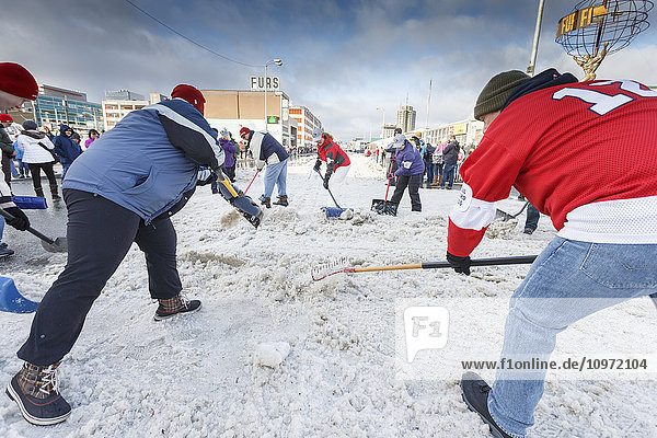 Freiwillige schaufeln an einer Straßenkreuzung auf der 4th Avenue während des feierlichen Starttages des Iditarod 2015 in Anchorage  Alaska  Schnee auf die Strecke zurück
