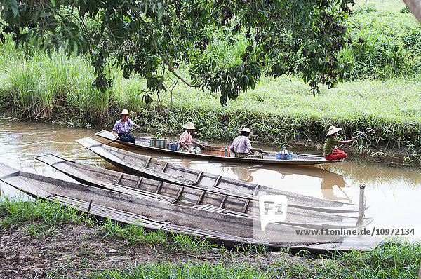 'People riding in a traditional boat down a river; Myanmar'