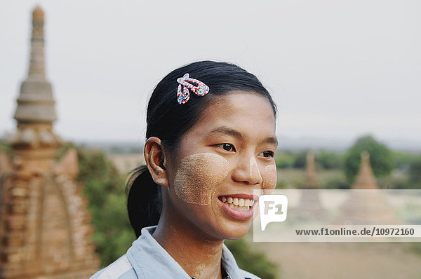 'A young woman smiling with a temple in the background; Bagan  Myanmar'