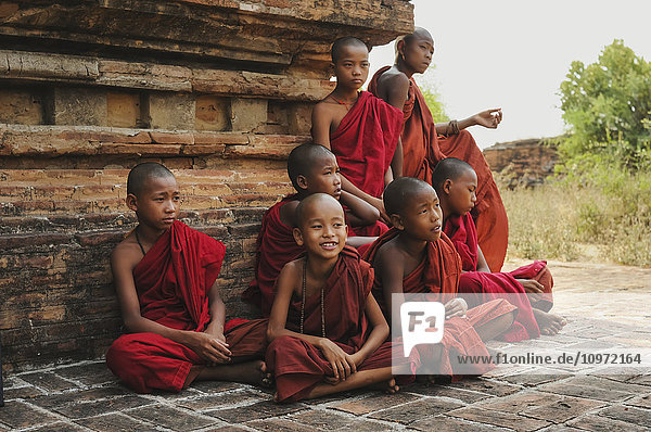 'Buddhist monks gathered outside a building; Mayanmar'