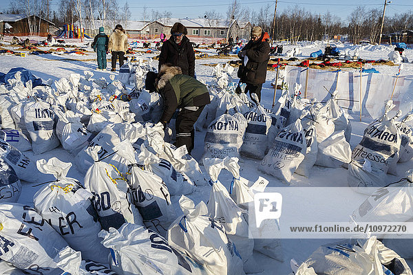 Freiwillige Helfer bereiten am Nachmittag am Huslia-Kontrollpunkt während des Iditarod 2015 Verpflegungsbeutel für Musher vor.