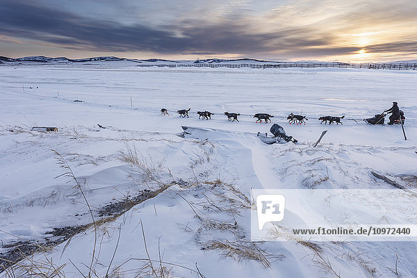 Curt Perano läuft bei Sonnenaufgang aus dem Unalakleet-Kontrollpunkt während des Iditarod 2015