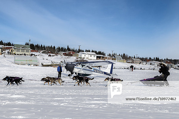 Jessie Royer runs past an airplane as she arrives in the afternoon at the White Mountain checkpoint during Iditarod 2015