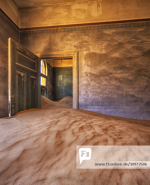 Sand in den Räumen eines bunten und verlassenen Hauses; Kolmanskop  Namibia