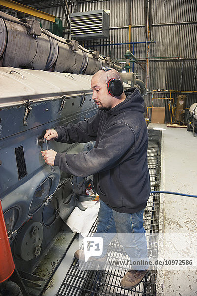 Ein männlicher hispanischer Arbeiter repariert einen Dieselgenerator in einem Elektrizitätswerk  Prudhoe Bay  Arktisches Alaska  USA  Sommer