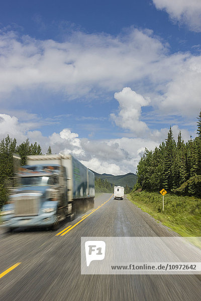 RV camper drives past a semi truck on the Alaska Highway  west of Fort Nelson  British Columbia Canada  Summer