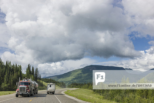 Pick up truck camper drives past a semi truck on the Alaska Highway  west of Fort Nelson  British Columbia Canada  Summer