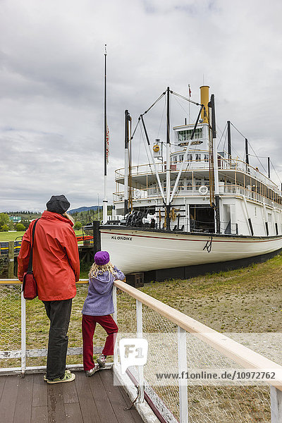 Mother and daughter stand on a viewing platform looking at the SS Klondike  Whitehorse  Yukon Territory  Canada  summer