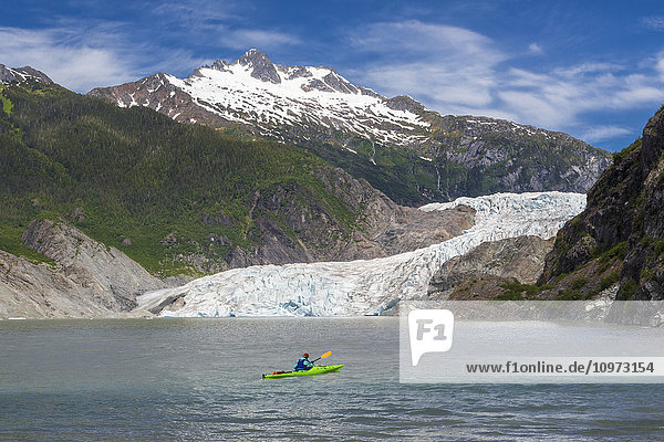 View of the Mendenhall Glacier with a kayaker on Mendenhall Lake in the foreground near Juneau  Southeast Alaska  Summer.
