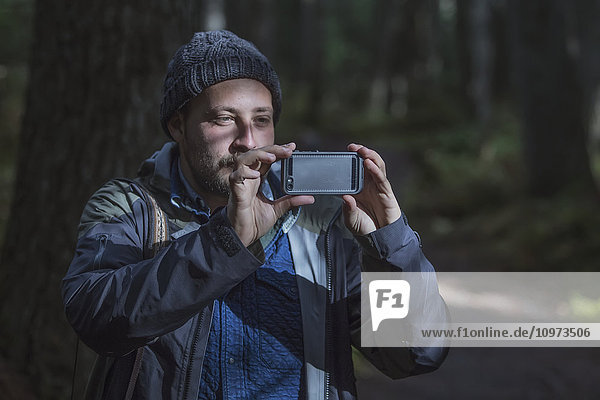 'Man photographing the forest around Girdwood with his smartphone  Southcentral Alaska.'