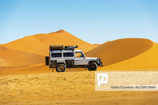 Land Rover Defender 110 geparkt in der Wüste mit Dünen in der Ferne; Sossusvlei  Namibia'.