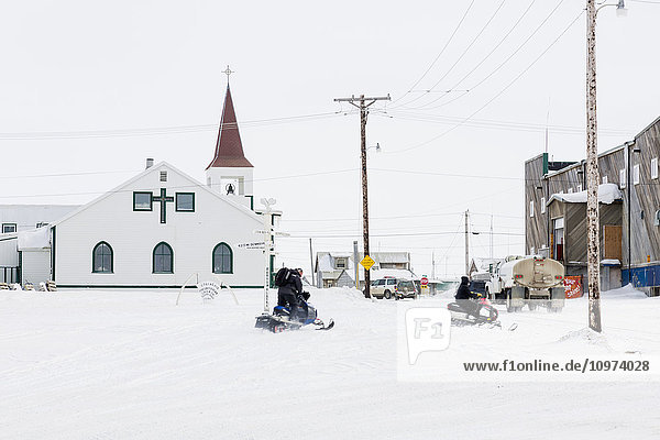 Zwei männliche Alaskaner fahren Motorschlitten in der Innenstadt von Barrow  North Slope  Arctic Alaska  USA  Winter'.
