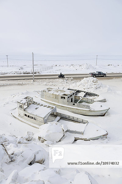 Kleine Boote eingefroren in Schneebänken neben einer Straße  Meereis im Hintergrund  Barrow  North Slope  Arctic Alaska  USA  Winter