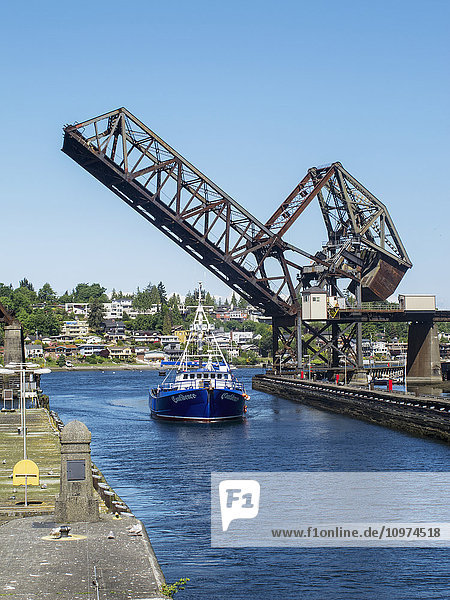 Ein Schiff in einem Kanal fährt an einem klaren sonnigen Tag unter der erhöhten Brücke hindurch  Ballard Locks  Seattle  Washington  Sommer  USA