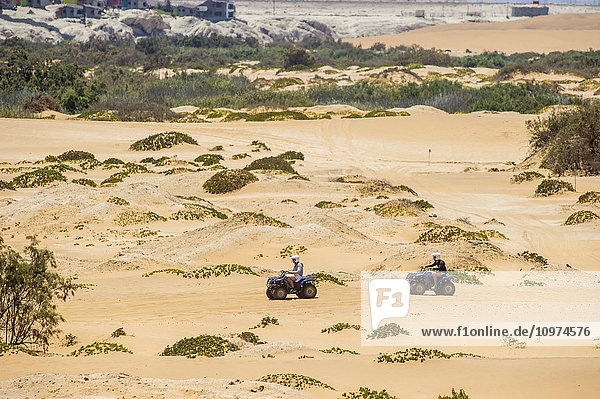 Zwei Menschen fahren mit einem Geländewagen durch die Wüste; Swakopmund  Namibia'.