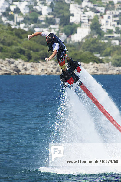 Flyboarder  der aus großer Höhe ins Wasser springt; Torba  Provinz Mugla  Türkei'.