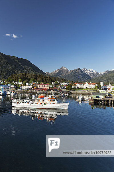 A passenger ship departs from Sitka Harbor with Sitka and the Three Sisters mountains in the background  Southeast Alaska  USA  Summer